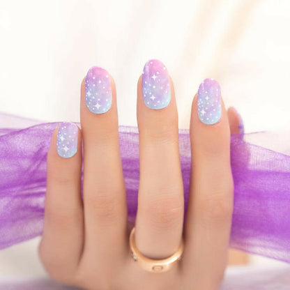 Hand wearing pastel ombre nail wraps with white dots and celestial design