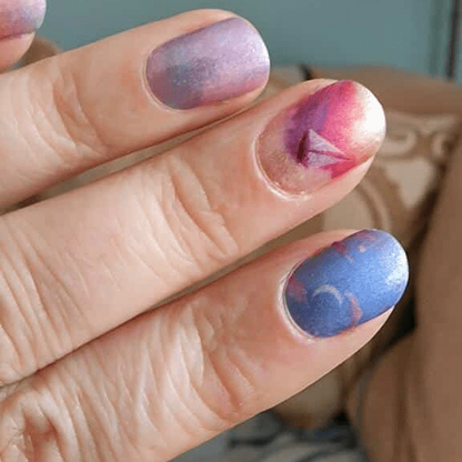Close-up starry night nail wraps on fingertips blue purple gradient cosmic manicure design