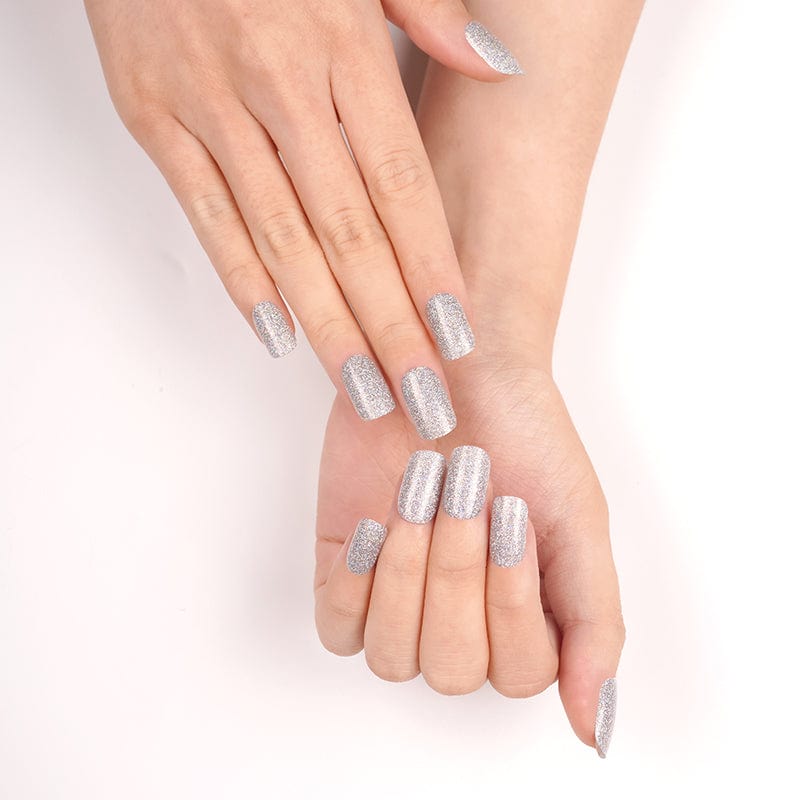 Silver glittery gel nail wraps on crossed hands showing sparkly at-home manicure