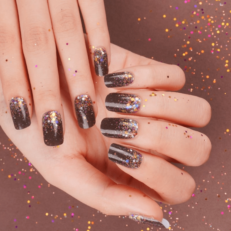Hands wearing black glitter nail wraps with multicolour confetti sparkle design