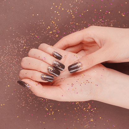 Cupped hands showing black sparkle nail wraps with rainbow glitter confetti pattern