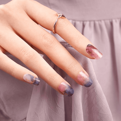 Hand with ring displaying abstract marble nail wraps in pink navy watercolour finish
