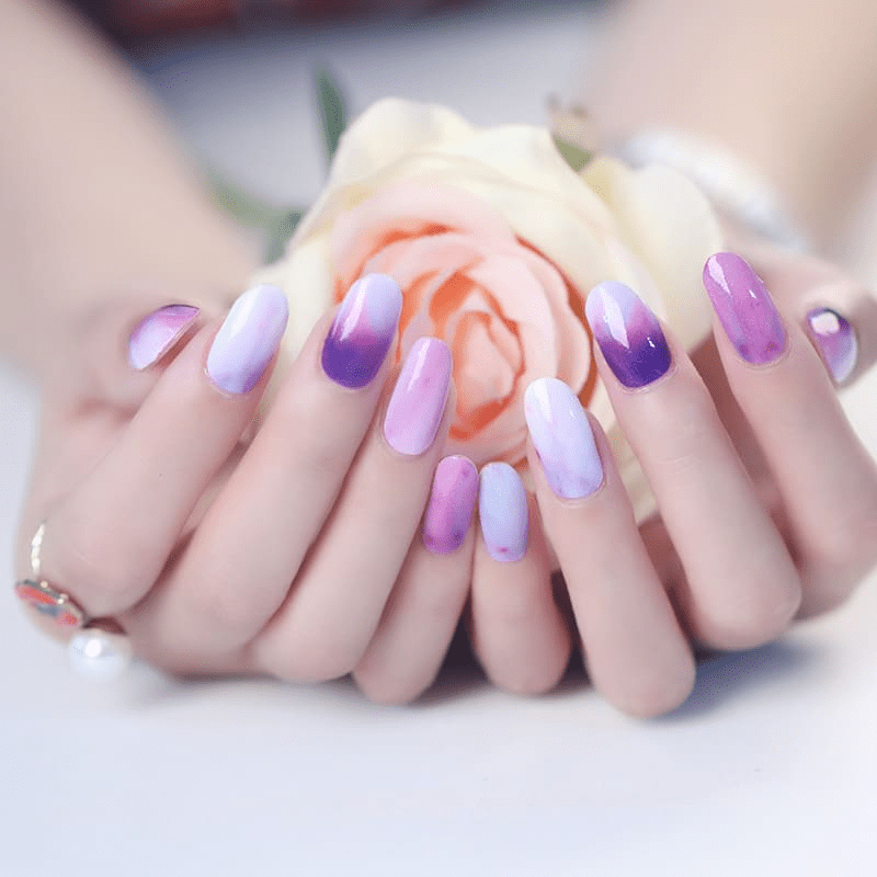 Purple gradient ombre nail wraps on hands holding pink rose with glossy finish