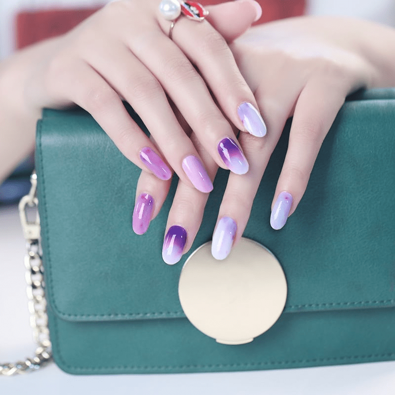 Purple ombre nail art wraps on hands with green handbag accessory