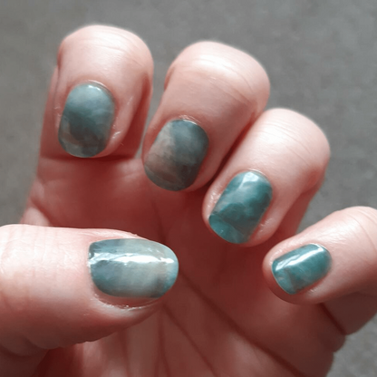 Stormy sea marble nail wraps applied on hand showing teal stone pattern