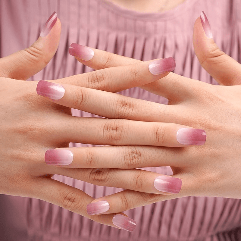 Woman's hands showing dusty rose ombre nail art against pink pleated fabric