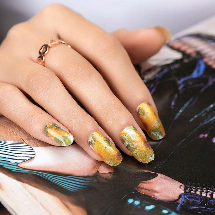 Hand with yellow sunflower botanical nail wraps holding magazine