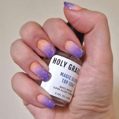 Hand holding magic gum top coat with purple to peach gradient glitter nail art