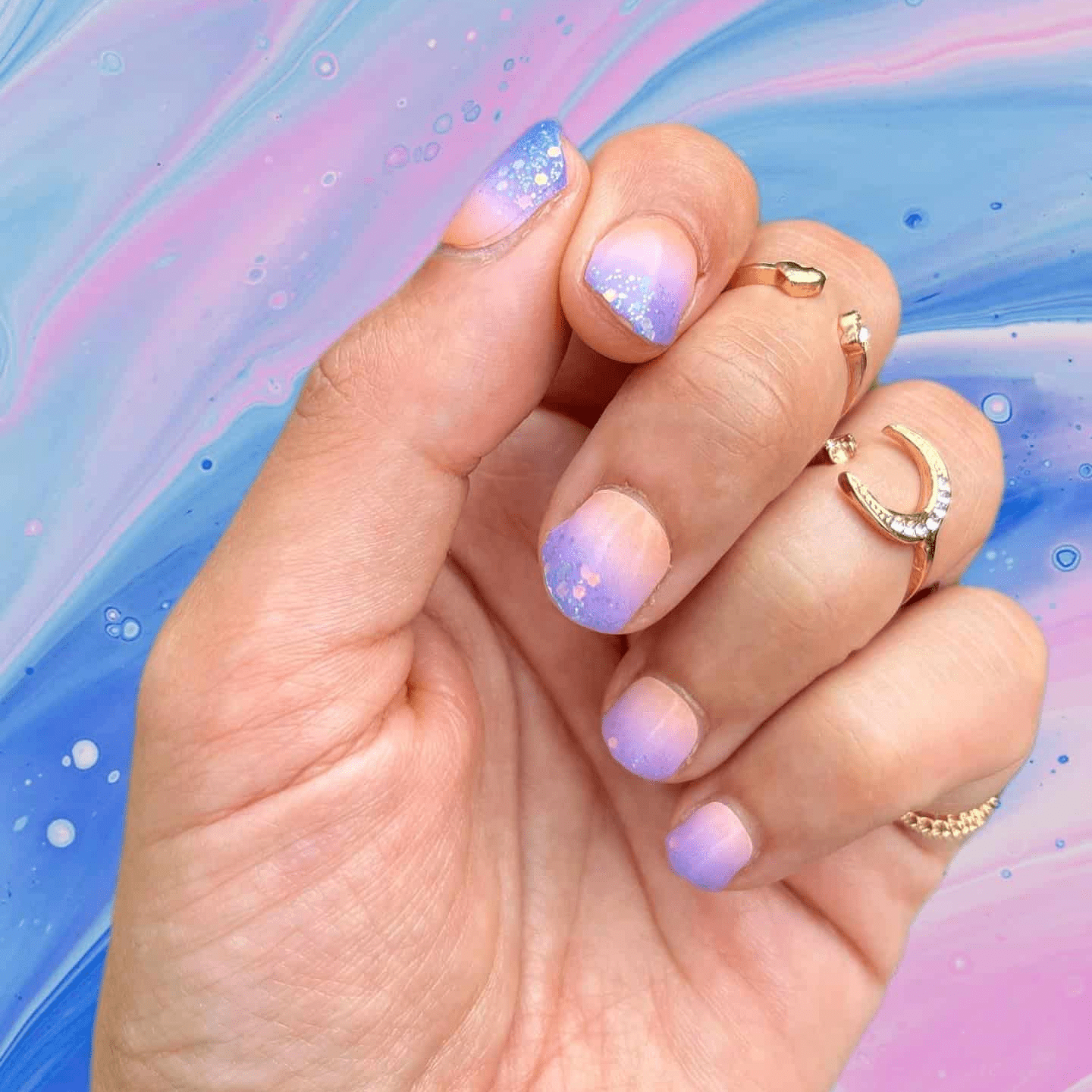 Hand displaying purple ombre glitter nail wraps with gradient sunset manicure design