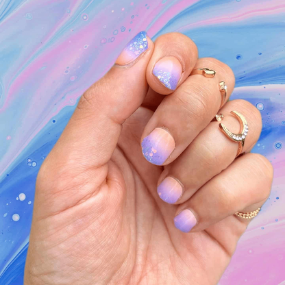 Hand displaying purple ombre glitter nail wraps with gradient sunset manicure design