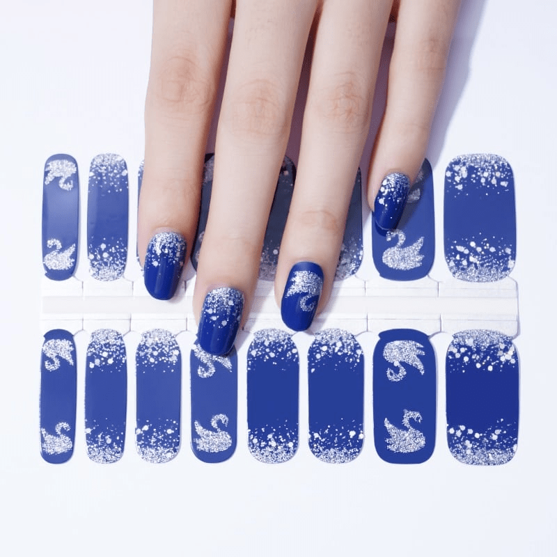 Navy blue nail wraps with silver glitter swan patterns on hand showing elegant nail art