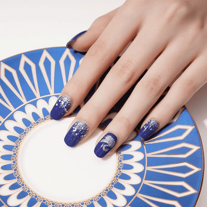 Blue nail wraps with silver swan design on decorative plate showcasing at-home manicure