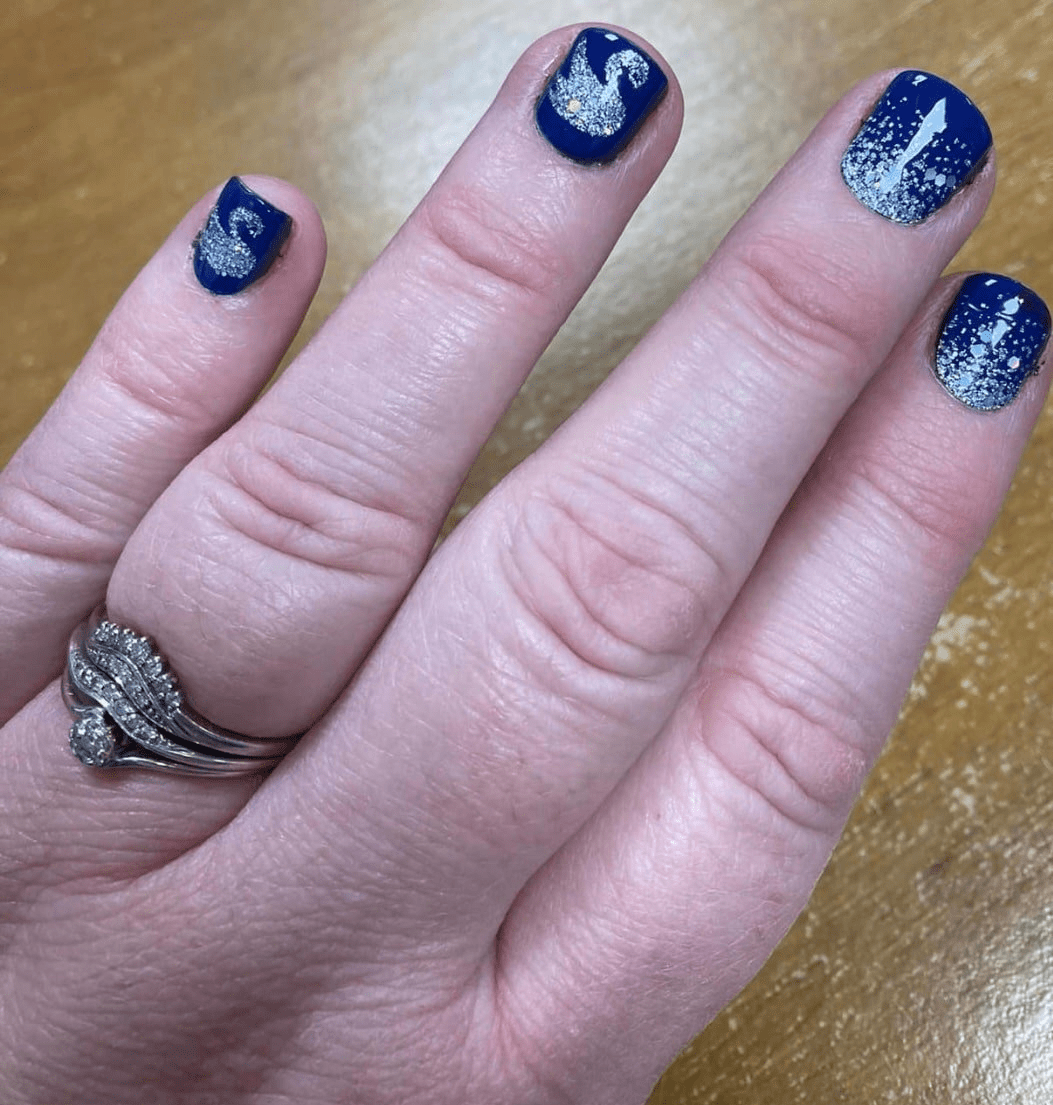 Navy blue nail wraps with silver swan and glitter dots applied on hand