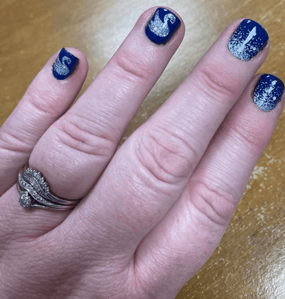 Navy blue nail wraps with silver swan and glitter dots applied on hand