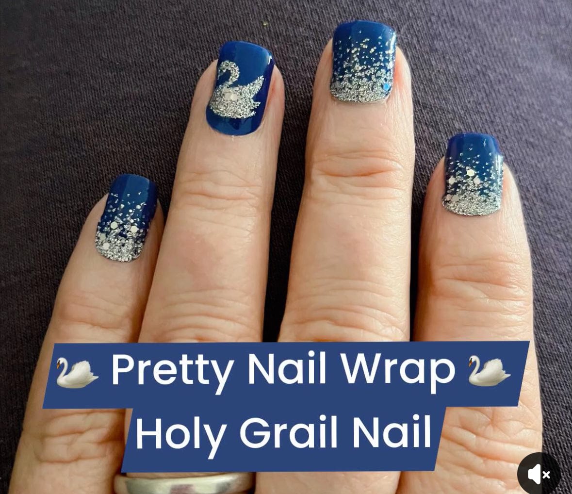 Hand displaying navy nail wraps with silver glitter swans for elegant nail art