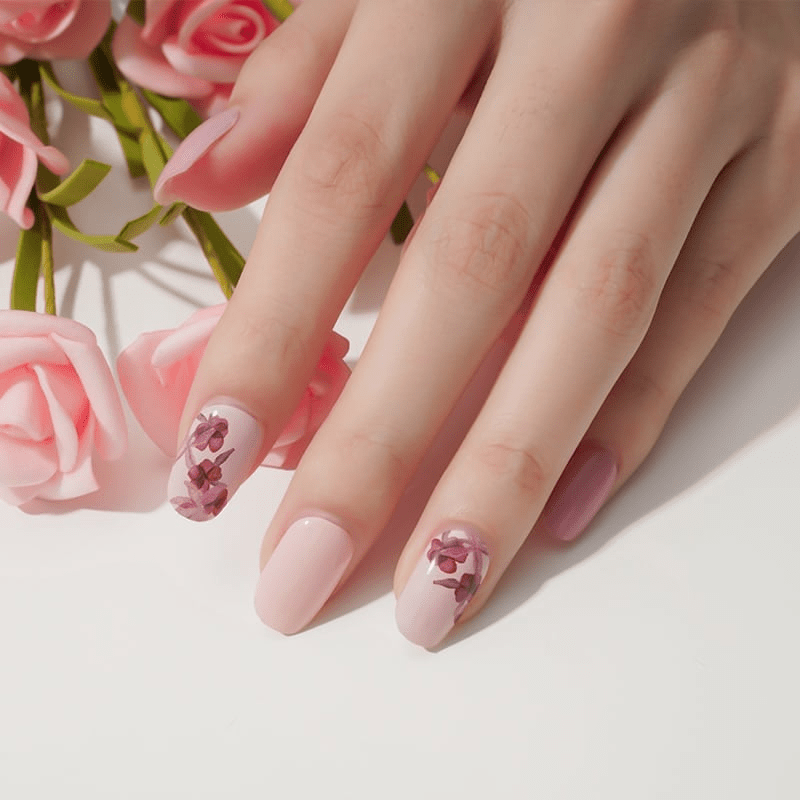 Pink rose nail wraps manicure with burgundy floral accents beside fresh roses