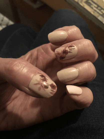 Hand wearing dusty pink nail wraps with burgundy rose floral pattern for romantic manicure