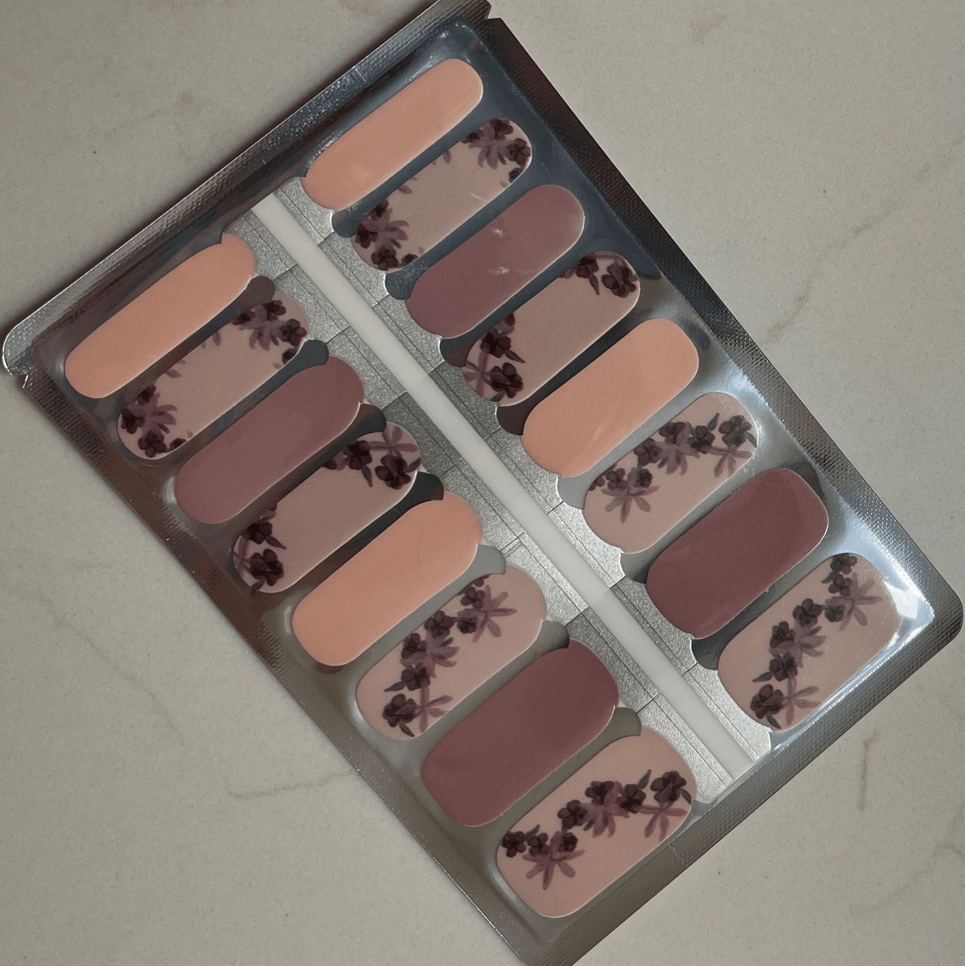 Sheet of dusty pink nail wraps featuring burgundy rose floral patterns for at-home manicure