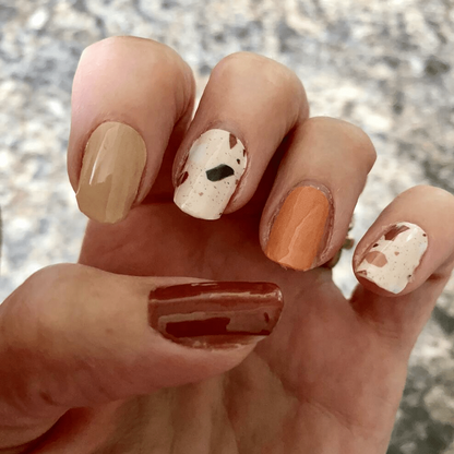 Autumn terrazzo nail art on hand with brown orange and cream speckled pattern