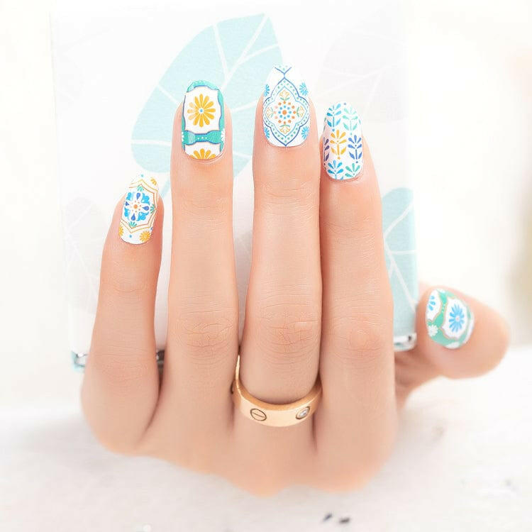 Hand displaying retro botanical nail art wraps with 70s daisy and geometric designs