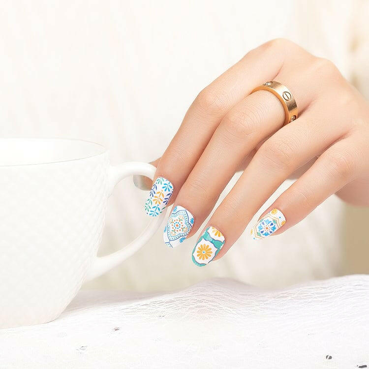 Hand with vintage floral nail wraps featuring blue orange retro patterns and designs