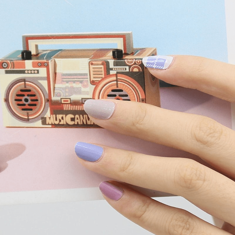 Blue and purple nail wraps on hand holding retro boombox with tartan design