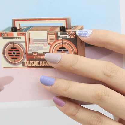 Blue and purple nail wraps on hand holding retro boombox with tartan design