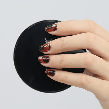 Tortoiseshell nail wraps with gold metallic accents displayed on black surface