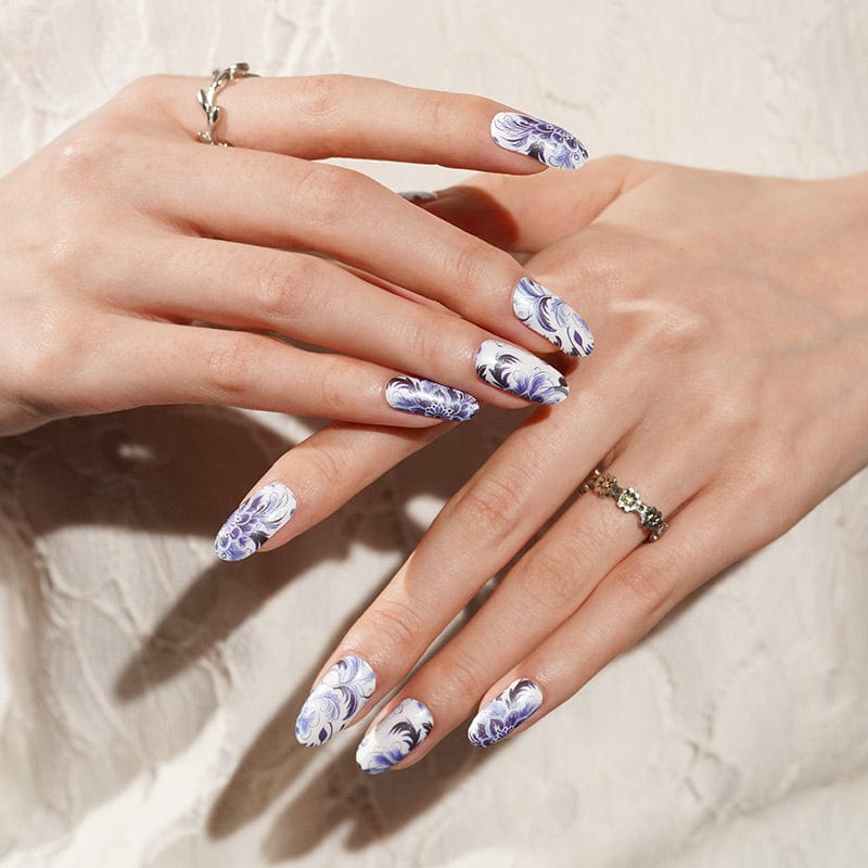 Blue and white floral nail wraps on hands featuring delicate porcelain pattern for at-home manicure