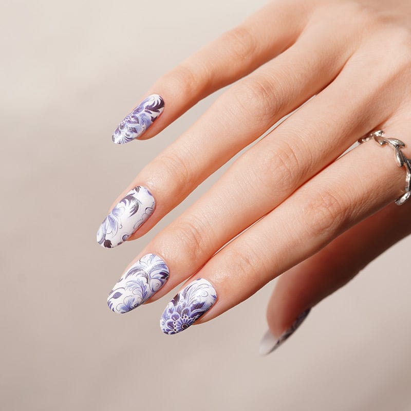 Blue floral nail wraps on hand showing vintage porcelain swirl pattern design