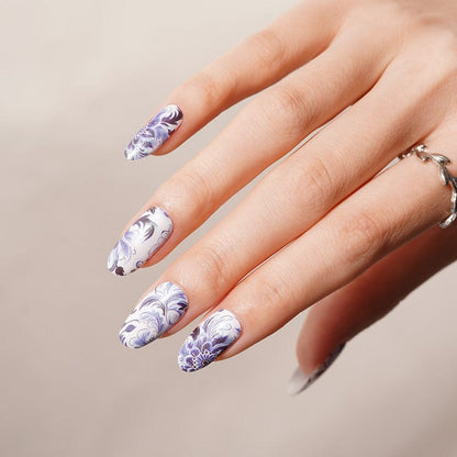 Blue floral nail wraps on hand showing vintage porcelain swirl pattern design