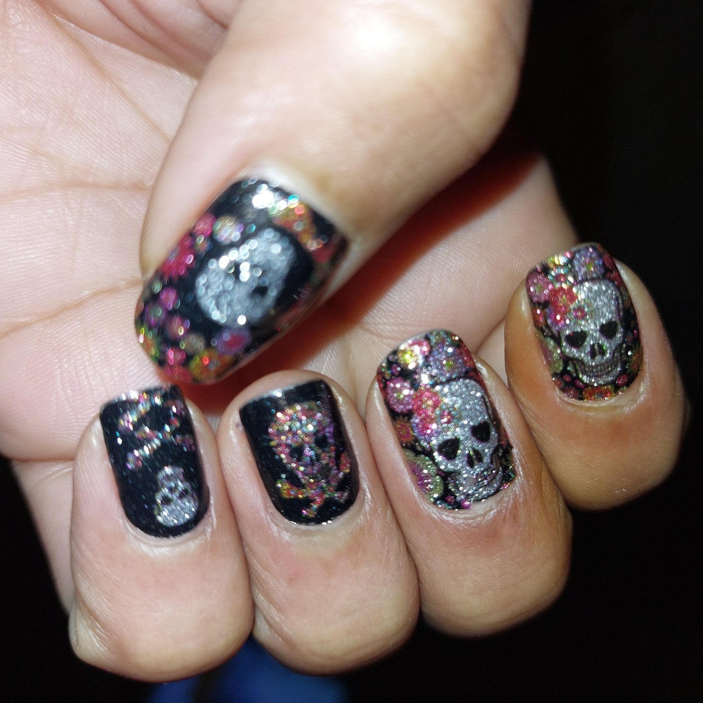 Black nail wraps with colourful sugar skull and floral Day of the Dead design on hand