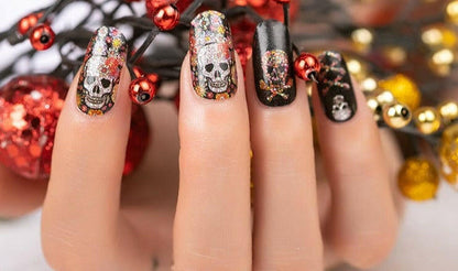 Glittery skull nail art wraps on hand showing Day of the Dead design for Halloween