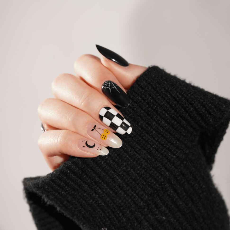 Gothic Halloween nail art on hand featuring black checkerboard and spooky character designs