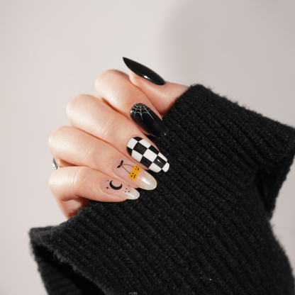 Gothic Halloween nail art on hand featuring black checkerboard and spooky character designs