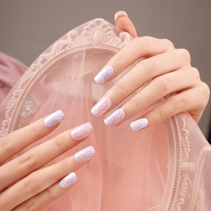 Soft pink botanical nail wraps on hands showing feminine floral lace design for bridal manicure