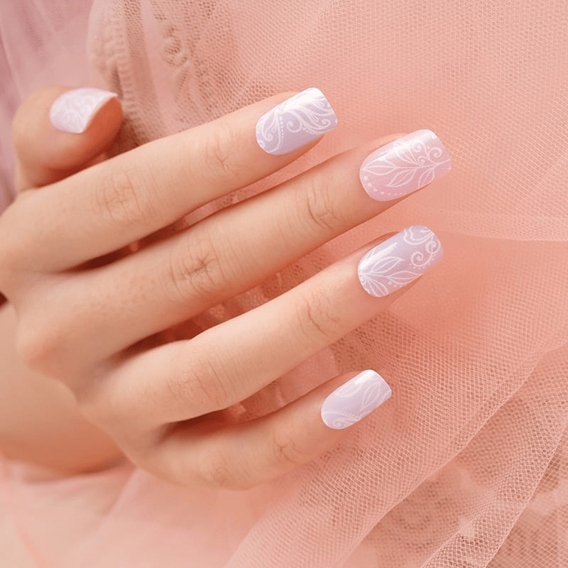 Hand wearing pink floral nail wraps with delicate botanical pattern against pink tulle background