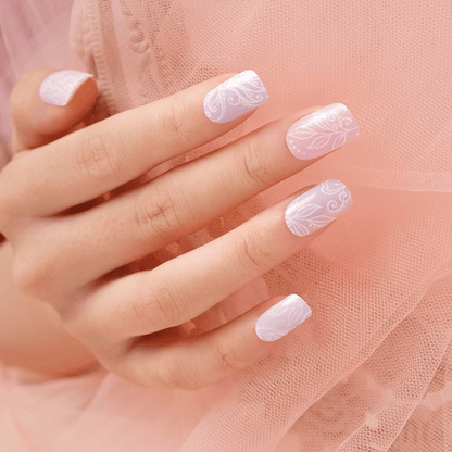 Hand wearing pink floral nail wraps with delicate botanical pattern against pink tulle background