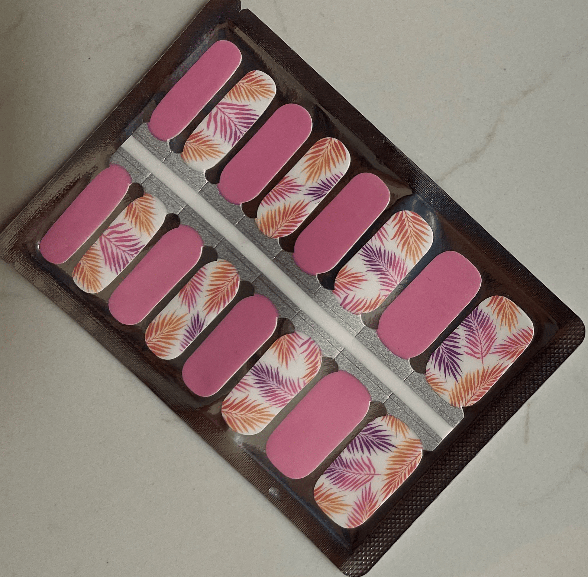 Pink coral nail wraps with tropical fern leaf pattern in packaging