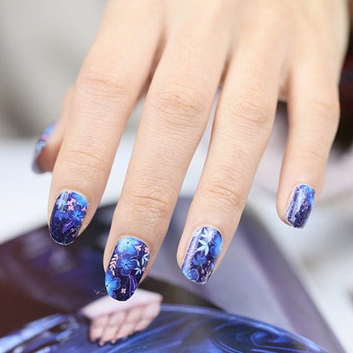 Blue tropical floral nail wraps on hand showing navy watercolour botanical design