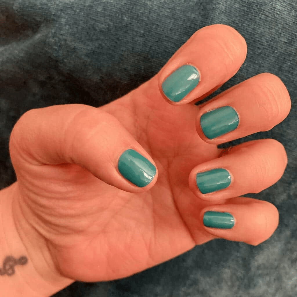 Glossy teal nail wraps on hand showing professional at-home manicure results