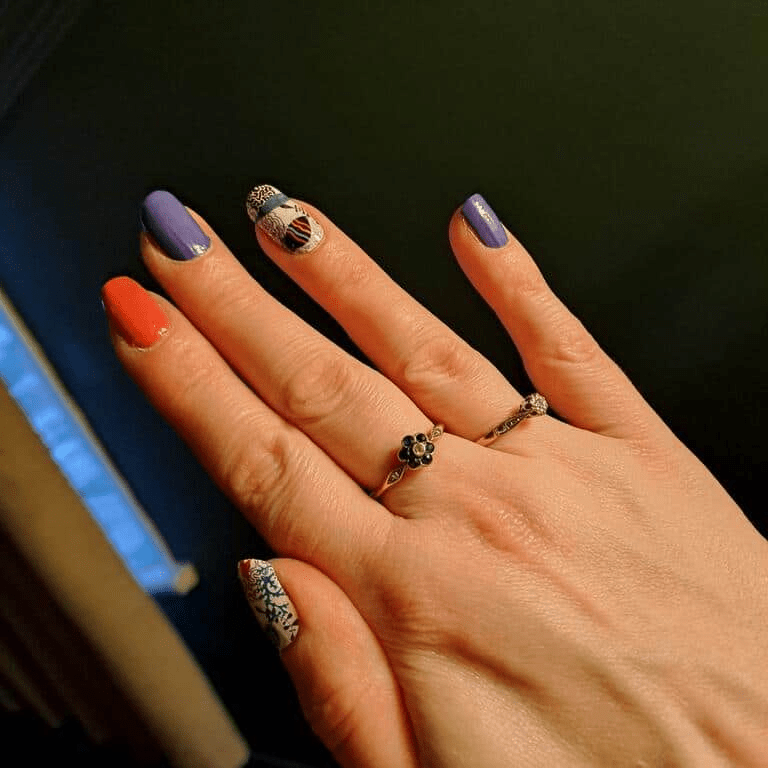Ocean themed nail wraps in blue and orange with seahorse designs on fingers at-home manicure