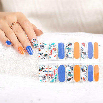 Hand applying ocean themed nail wraps with seahorse coral and blue patterns for nail art