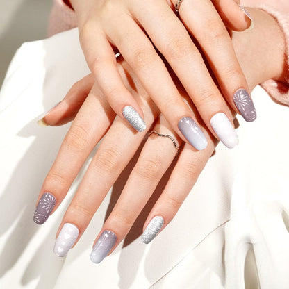 Hands displaying grey and white non-UV nail wraps with shimmer and geometric nail art