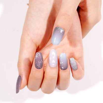 Hand wearing grey metallic nail wraps with silver glitter and geometric patterns, at-home manicure