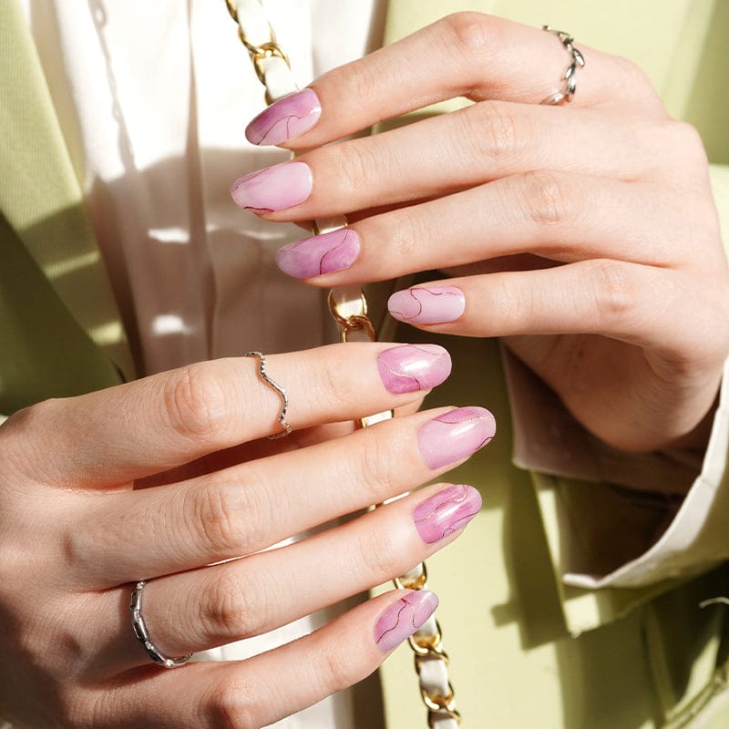 Hand wearing pink marble effect nail wraps with dusty rose cream finish