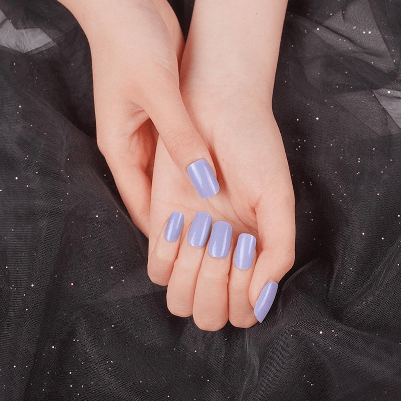 Cupped hands displaying lavender purple glossy nail wraps against dark sparkly fabric background