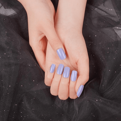 Cupped hands displaying lavender purple glossy nail wraps against dark sparkly fabric background
