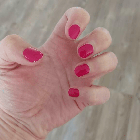Hand displaying hot pink gel nail wraps with high-gloss finish for at-home nail art