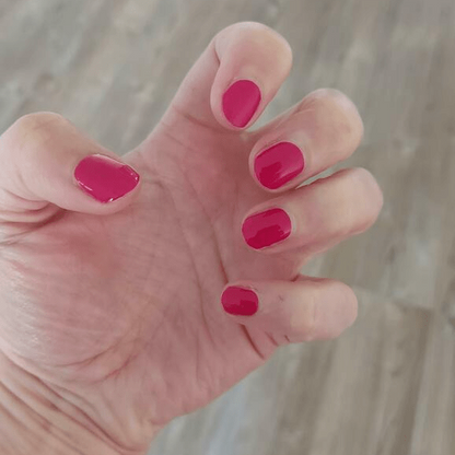 Hand displaying hot pink gel nail wraps with high-gloss finish for at-home nail art